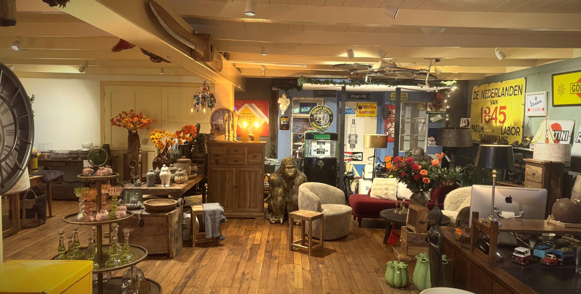 De winkel van binnen vol meubels, vintage reclameborden, vazen, bloemen en bijzondere vondsten