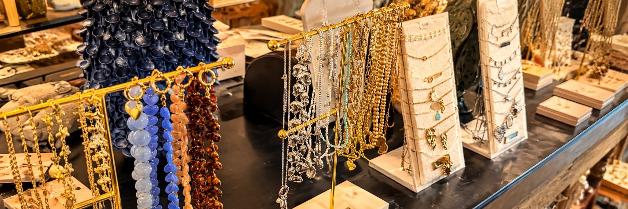Kettingen in goud, zilver en kleur aan gouden rekjes en op witte displays in de winkel
