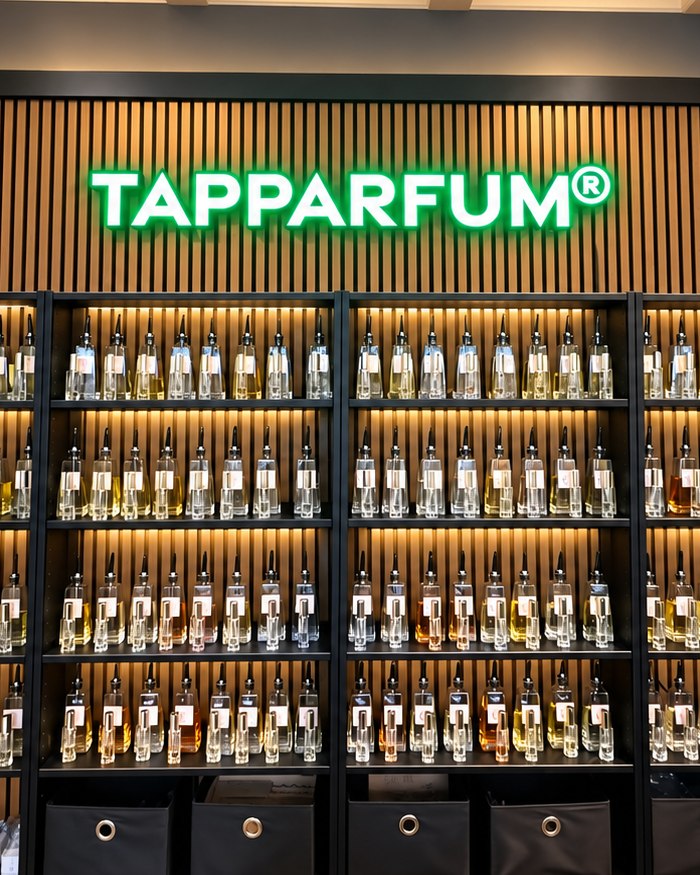Kasten vol tapparfum onder de groene TAPPARFUM-lichtreclame